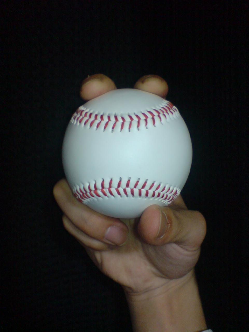 Front view · ball and fingers of Two-seam fastball; Two-seam example: the ball orientation differs from the four-seam hold. Finger pads partly hide seam contact; ask your coach to show the paired seams under the fingers.